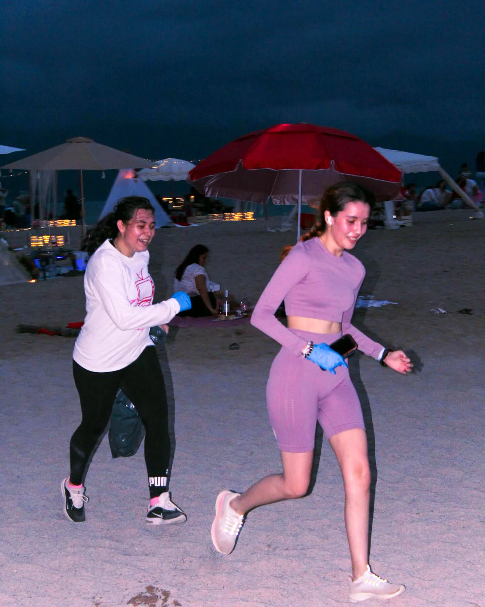 Dos corredoras con guantes azules en la playa