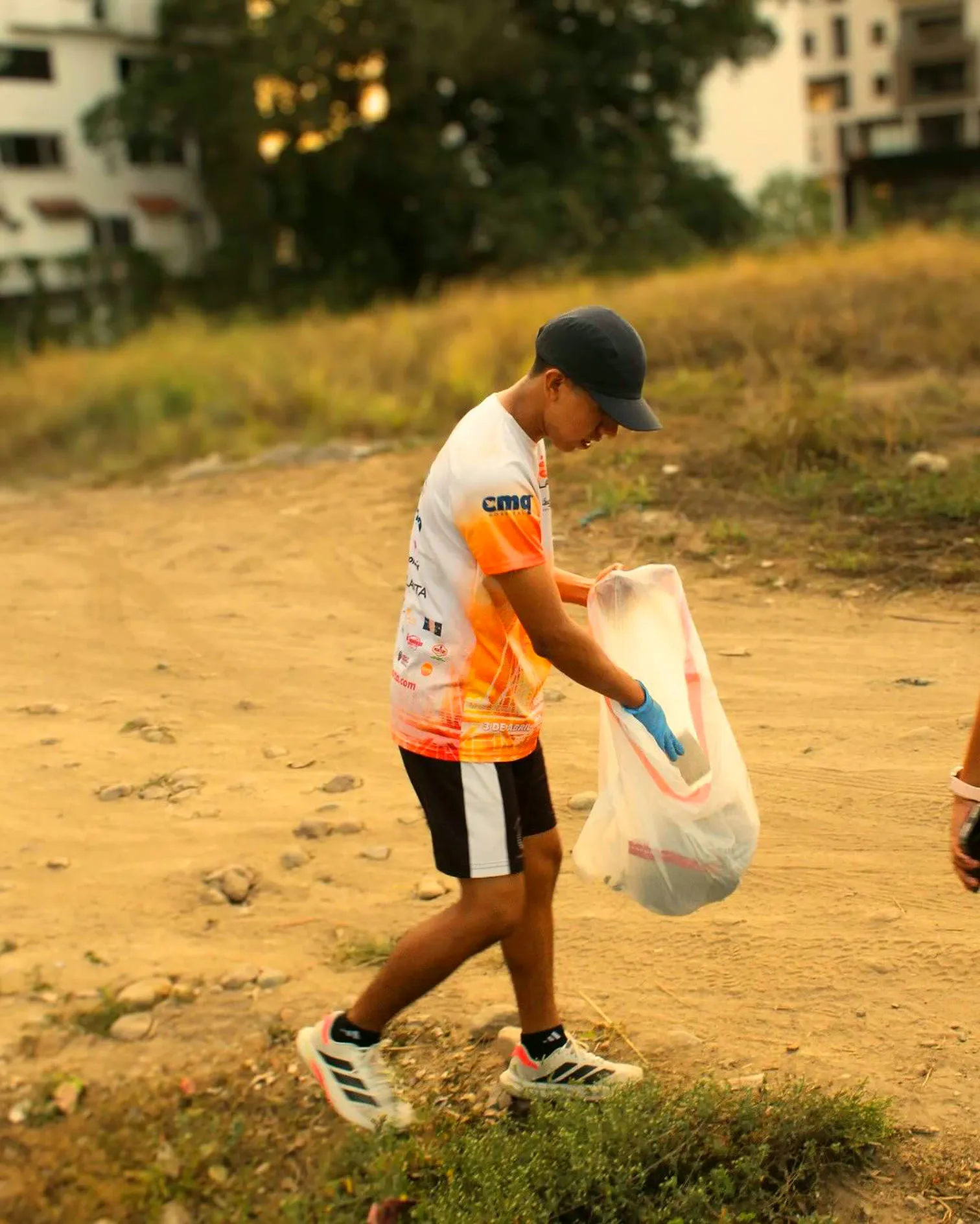 Corredor recogiendo basura con su bolsa en un terreno